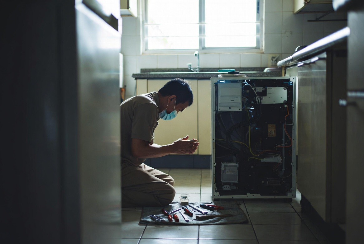 Technician diagnosing an opened appliance in a Singapore home kitchen